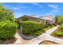 Landscaped home exterior featuring mature shrubbery and sidewalks with desert-style flower beds at 2480 Domingo St, Las Vegas, NV 89121