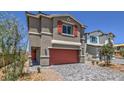 Two-story home featuring brick driveway, desert landscaping, and red shutters and garage door at 2617 Snapdragon Falls Ave # 100, North Las Vegas, NV 89081