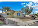 A quaint yellow house with fresh xeriscaping, a driveway, and sidewalk at 4419 Fairmont Cir, Las Vegas, NV 89147
