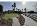 Common area with manicured lawn, walking path, white fence, and palm trees at 6459 Rusticated Stone Ave # 103, Henderson, NV 89011