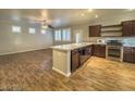 Kitchen and living room combination with wood floors, ceiling fan, stainless appliances, and center island at 6777 Wormwood Ln, Las Vegas, NV 89148