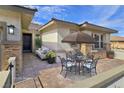 Inviting outdoor patio with comfortable seating, a table with umbrella, and stylish brick pavers at 701 Monroe Hill Pl, Henderson, NV 89011