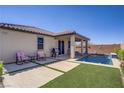 Inviting backyard with a sparkling pool, covered patio, and synthetic grass at 748 Dellenbaugh Ct, Las Vegas, NV 89178