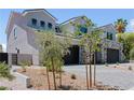 View of the side of a two-story home featuring stone accents, a three-car garage, and desert landscaping at 8721 Robinson Ridge Dr, Las Vegas, NV 89117
