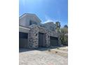 Spacious three-car garage with a sleek gray door and brick-paved driveway, perfect for car enthusiasts at 8721 Robinson Ridge Dr, Las Vegas, NV 89117