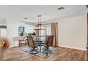 A stylish dining area showcases a glass table, modern chandelier, and seamless flow into the kitchen at 976 El Camino Way, Boulder City, NV 89005