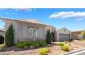 Inviting single-story home featuring stone accents, lush shrubs, and a convenient two-car garage at 10579 Garden Rose Dr, Las Vegas, NV 89135