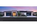 Stunning modern home with stone facade, two-car garages and manicured landscaping, sunset sky at 11152 San Terrazo Pl, Las Vegas, NV 89141