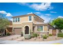 View of a two-story tan home with a two-car garage, arched entryway, and well-maintained front yard landscaping at 2198 Maderno St, Henderson, NV 89044