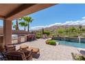 Inviting pool patio with outdoor kitchen, ample seating, and picturesque mountain views at 2539 Turtle Head Peak Dr, Las Vegas, NV 89135