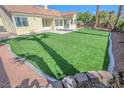 A spacious backyard featuring well-manicured artificial turf, concrete patios, and desert landscaping at 4416 Inez Dr, Las Vegas, NV 89130