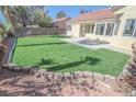 Backyard featuring green synthetic grass, mature trees, a cinderblock wall, and a concrete patio at 4416 Inez Dr, Las Vegas, NV 89130