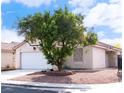 Inviting single-story home with a spacious front yard and mature tree under a partly cloudy sky at 5541 Alvarez St, North Las Vegas, NV 89031