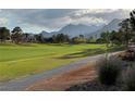 Scenic view of the golf course with mountains in the background; lush green fairway and walking path at 9369 Villa Ridge Dr, Las Vegas, NV 89134