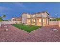A neatly landscaped backyard with artificial grass, decorative rocks, a covered patio and a two story home at 1136 Casady Hollow Ave, Henderson, NV 89012