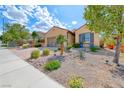 Landscaped front yard featuring drought-resistant plants, rock beds, and mature trees at 2601 Bechamel Pl, Henderson, NV 89044