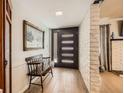 Inviting entryway featuring a modern door, wood flooring, and a bench beneath a charming painting at 2748 Heritage Cir, Las Vegas, NV 89121