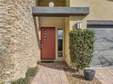 Close up shot of front entrance with a stone accent wall, red door, and desert landscaping at 3008 Barrett Springs Ave, Henderson, NV 89044