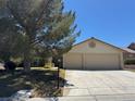 Inviting home exterior with a spacious driveway leading to a two-car garage and mature landscaping at 5121 Burr Oak Dr, Las Vegas, NV 89130