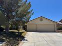 Lovely single-Gathering home showcasing a two-car garage, warm paint tones, and lush front lawn at 5121 Burr Oak Dr, Las Vegas, NV 89130
