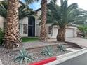 Beautiful home featuring an arched entry door, mature palm trees, and a three car garage at 7109 Rancho De Taos, Las Vegas, NV 89130