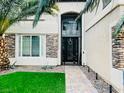 Inviting front entrance with a secure iron gate, stone accents, and lush green lawn at 7109 Rancho De Taos, Las Vegas, NV 89130