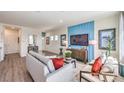 A bright living room with modern furniture, light wood flooring and a blue accent wall with a TV at 4755 Bluebird Cliffs Ave Dr # Lot 173, Las Vegas, NV 89141