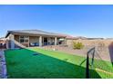 Inviting backyard featuring artificial grass, covered patio, desert landscaping, and block wall perimeter at 10095 Ferton Lake Ave, Las Vegas, NV 89178