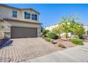 A well-kept home featuring a large two-car garage, a brick driveway, and well-maintained landscaping at 104 Pollentia Ave, North Las Vegas, NV 89084