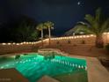 Nighttime view of a backyard pool illuminated with vibrant green lights, palm trees, and ambient string lights at 11143 Castellane Dr, Las Vegas, NV 89141