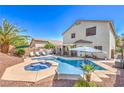 Relaxing backyard oasis boasts a sparkling pool with a jacuzzi, palm trees, and lounge area at 11143 Castellane Dr, Las Vegas, NV 89141