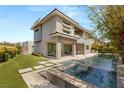 Backyard view showcasing a modern pool, integrated hot tub, covered patio, and lush green lawn at 15 Gemstar Ln, Las Vegas, NV 89135