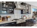 This kitchen features modern stainless steel appliances, dark cabinets, wine cooler and a patterned backsplash at 2518 Veronella St, Henderson, NV 89044