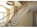 Elegant carpeted staircase with a wooden handrail leads to the upper level, enhanced by natural light at 2830 Queens Courtyard Dr, Las Vegas, NV 89109