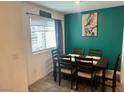 A modern dining area featuring a wooden table, chairs, and a vibrant green accent wall with decorative artwork at 2872 Atomic Tangerine Way # 2, Las Vegas, NV 89183
