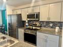 Well-equipped kitchen with stainless steel appliances, granite countertops, and stylish backsplash for modern cooking at 2872 Atomic Tangerine Way # 2, Las Vegas, NV 89183