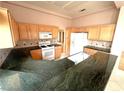 Open kitchen featuring black granite countertops, a white range, and lots of wooden cabinets at 2925 Big Green Ln, Las Vegas, NV 89134