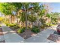 Exterior shot of a condo building showcasing lush landscaping and mature trees surrounding the property at 3845 Wiggins Bay St # 202, Las Vegas, NV 89129