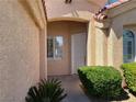 Inviting front entrance with a covered porch, complemented by lush greenery and a view of windows with shutters at 3882 Genoa Dr, Las Vegas, NV 89141