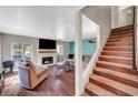 Inviting living room with a cozy fireplace, hardwood floors, and a staircase leading to upper level at 506 Chestnut View Pl, Henderson, NV 89052
