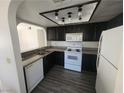 Galley style kitchen with black cabinets, white appliances, and new floors at 611 Bass Dr # C, Henderson, NV 89014