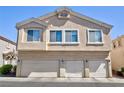 Exterior shot of a three-story home, featuring three garage doors and beige stucco at 6420 Extreme Shear Ave # 102, Henderson, NV 89011