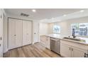 Open kitchen view with quartz counters, stainless steel sink, white cabinets and wood-look flooring at 9303 Gilcrease Ave # 1243, Las Vegas, NV 89149