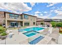 Resort style pool with attached spa, sun loungers, outdoor kitchen, and fire feature in this attractive backyard at 2153 King Crest Ct, Henderson, NV 89052