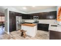 Modern kitchen with dark wood cabinets, stainless steel appliances, island and stylish wood-look tile flooring at 2421 Sunrise Springs Ct, North Las Vegas, NV 89031