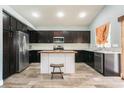 Modern kitchen with dark wood cabinets, stainless steel appliances, island and stylish wood-look tile flooring at 2421 Sunrise Springs Ct, North Las Vegas, NV 89031