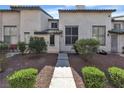 A townhome with well-maintained landscaping and a sidewalk leading to the front door at 2461 Old Forge Ln # 103, Las Vegas, NV 89121