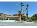 Desert landscape with a two-story home featuring palm trees, a terracotta roof, and a two-car garage at 4732 Illustrious St, Las Vegas, NV 89147