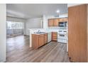 Well-lit kitchen featuring wood cabinets, white appliances, and wood flooring at 5710 E Tropicana Ave # 1017, Las Vegas, NV 89122