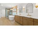 Bathroom featuring double sinks, wood cabinets, and a stand-alone bathtub next to a glass enclosed shower at 7616 Gossamer Wind St, Las Vegas, NV 89139